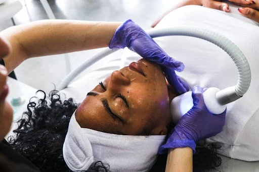 A practitioner applies a cryofacial wand to the forehead.